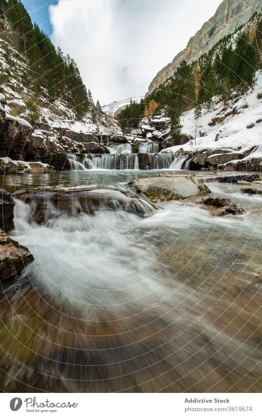 Wasserfall mit Pool zwischen schneebedeckten Bergen Berge u. Gebirge Schnee Wald Natur Landschaft Winter wild strömen malerisch Umwelt Felsen Harmonie kalt