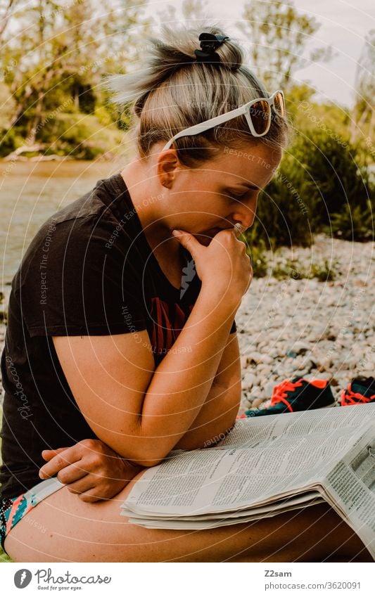 Junge Frau beim Lesen an der Isar isar strand lesen zeitung bildung nachrichten sonnebrille sommer entspannung erholung baden wärme einsam tageszeitung news