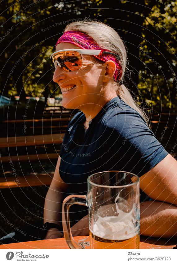 Radtour-Pause im Biergarten bayern biergarten radler trinken genießen entspanne lachen fröhlich glücklich entspannt sportlich trikot sonnebrille junge frau