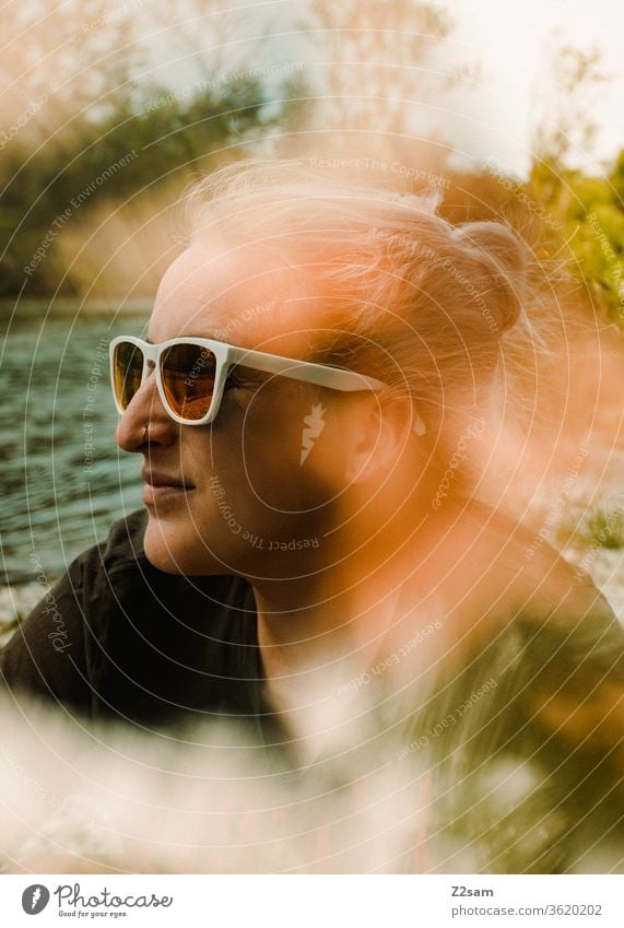 Junge Frau entspannt in der Sonne sommer sonne entspannung wasser fluß isar bayern sonnenbrille cool t-shirt blond mädchen frau jung lässig natürlich warm grün