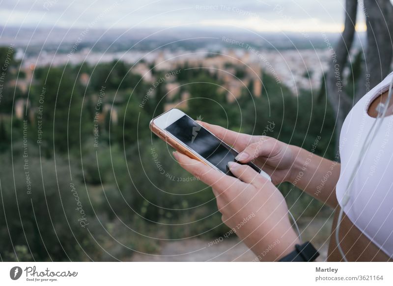 Hände eines jungen Mädchens beim Telefonieren in der Natur nach dem Sport. Beschneiden Sie eine ierkannte Frau mit der mobilen Tracking-App, während sie im Freien trainiert.