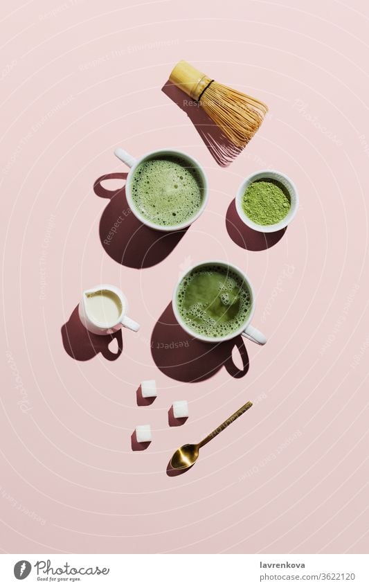 Veganer Matcha Latte mit Hafermilch auf rosa Pulver Schneebesen Milchkännchen Zucker Würfel Tasse Tee Japanisch Becher Getränk trinken Erfrischungen heiß