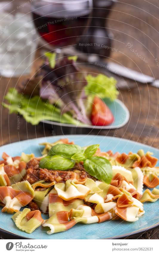 dreifarbige Pasta mit Fleischsauce tricolore Gabel Messer italienisch Fahne Farbe Pfeffermühle Planke Holz rustikal Mahlzeit Macaroni fusilli Nudel bolognese