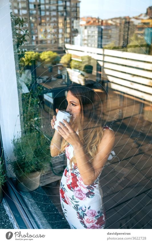 Frau trinkt Kaffee, während sie die Ansichten beobachtet Blick durch das Glas Fenster trinken Getränk Pause Reflexion & Spiegelung die Ansichten beobachten Tee