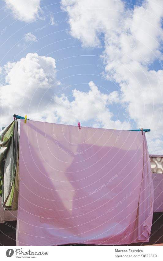 Kleider, die auf der Terrasse in der Sonne hängen. Himmel mit Sonne und Wolken im Sommer Wäscheklammer Konzept Stifte im Freien außerhalb Sonnenlicht luftfrei