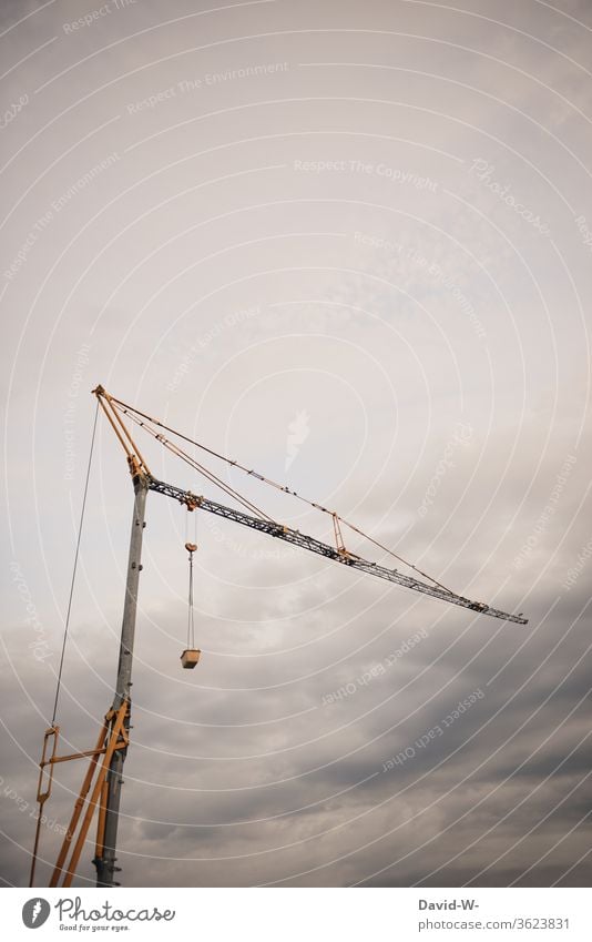 ein Kran auf einer Baustelle Himmel Wolken groß riesig hoch düster Gewitter Unwetter grau Baustop bauen Stillstand oben Textfreiraum Baugewerbe Kraft