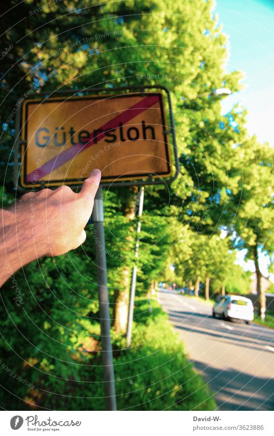 Mann zeigt auf das Ortsschild Gütersloh durchgestrichen Rheda-Wiedenbrück Oelde Absperrung abstand halten sicherheit covid-19 Tönnies Hotspots Corona-hotspots