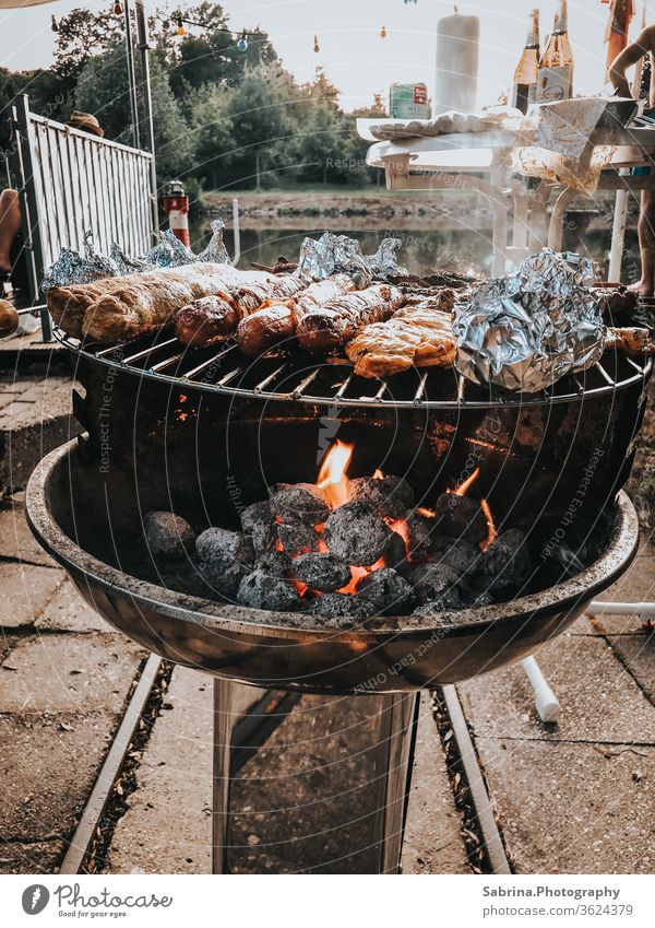 Grillen auf einem Holzkohlegrill an dem Fluss (Saale), Halle, Deutschland Halle (Saale) Halle Saale Sachsen-Anhalt Grillsaison Grillkohle Bootshaus Würstchen