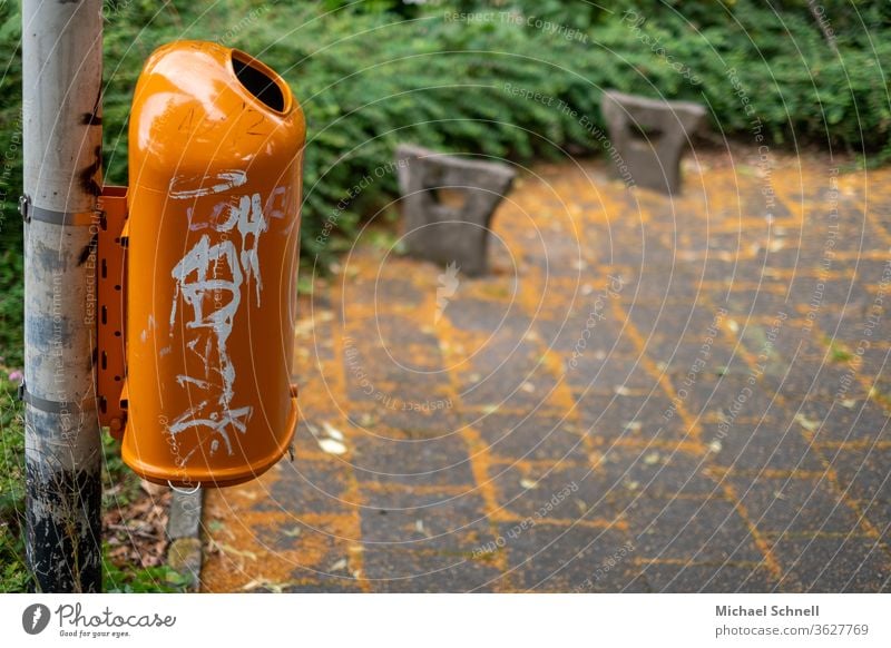 Oranger Mülleimer vor orangenen Blüten auf dem Boden Müllbehälter Umwelt dreckig Müllentsorgung wegwerfen Außenaufnahme