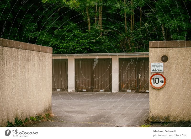 Alte Garagen in einem Garagenhof vor einem Waldgebiet braun alt trist langsam fahren Außenaufnahme Farbfoto Menschenleer