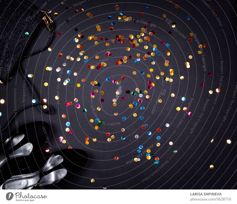 Set von Frauen Accessoires romantische Party kreative Komposition. Schuhe, Dekorationen und goldfarbenes Konfetti auf schwarzem Hintergrund. Draufsicht, Flachlegung, Kopierraum