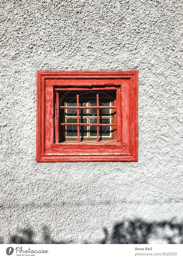 Das rote kleine Fenster auf der grauen Wand hat sie fasziniert. Sie stand lange davor und entdeckte noch den kleine.n Schatten gegenüber. Architektur Fassade