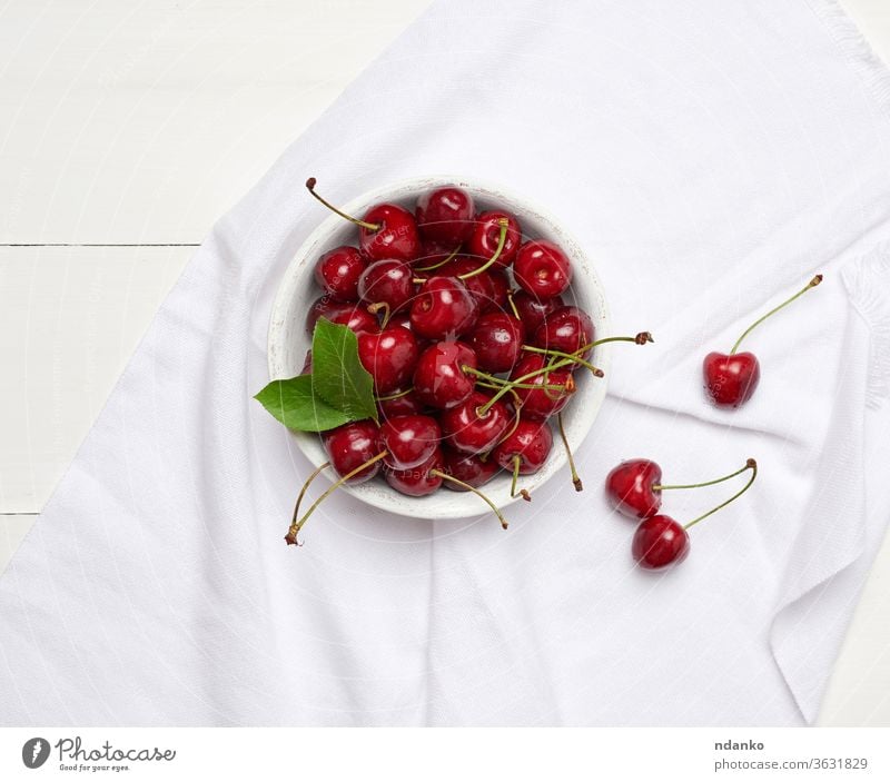 reife rote Kirsche in einer runden weißen Holzschale auf weißem Holzgrund Nahaufnahme Ernte lecker Dessert Ackerbau Hintergrund Beeren Schalen & Schüsseln