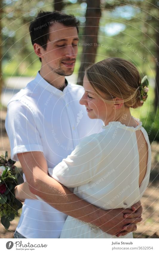 Brautpaar steht im Wald und umarmt sich brautpaar Haarschmuck Haare & Frisuren Sommer Lichteinfall grinsen Liebe Vertrauen genießen festhalten Brautstrauß weiß