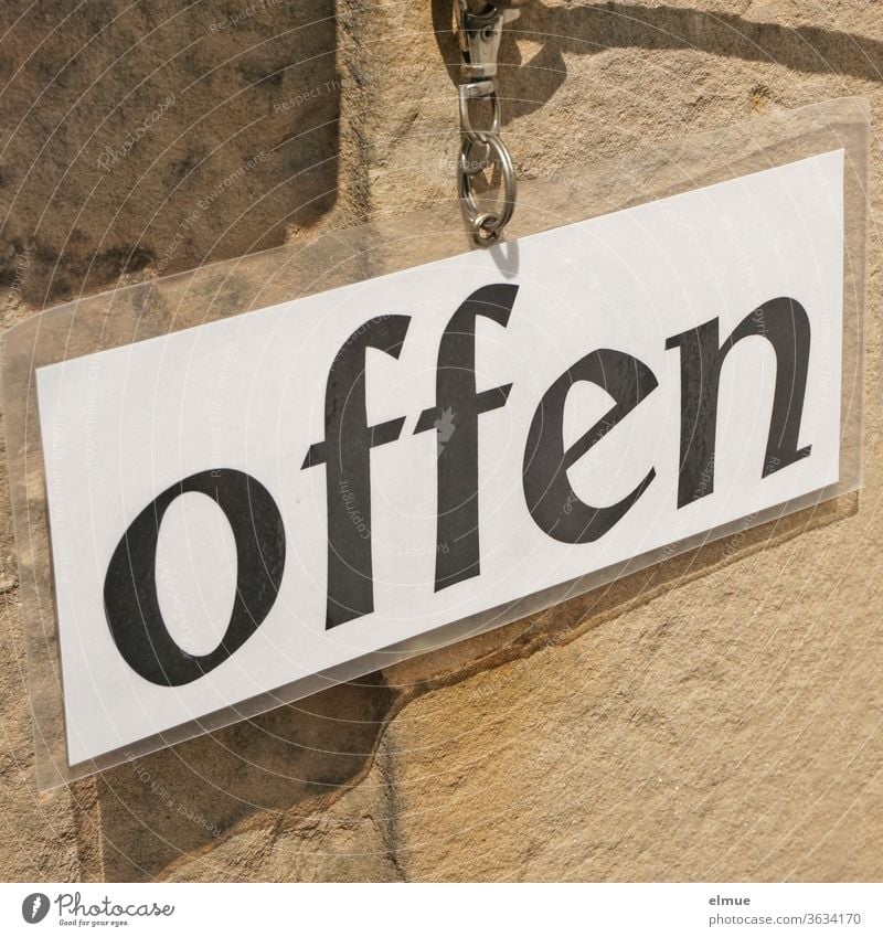 ein laminiertes weißes Blatt Papier mit schwarzer Schrift  "offen" ist mittels Metallring an einer Wand befestigt Schild geöffnet unverschlossen Einlass