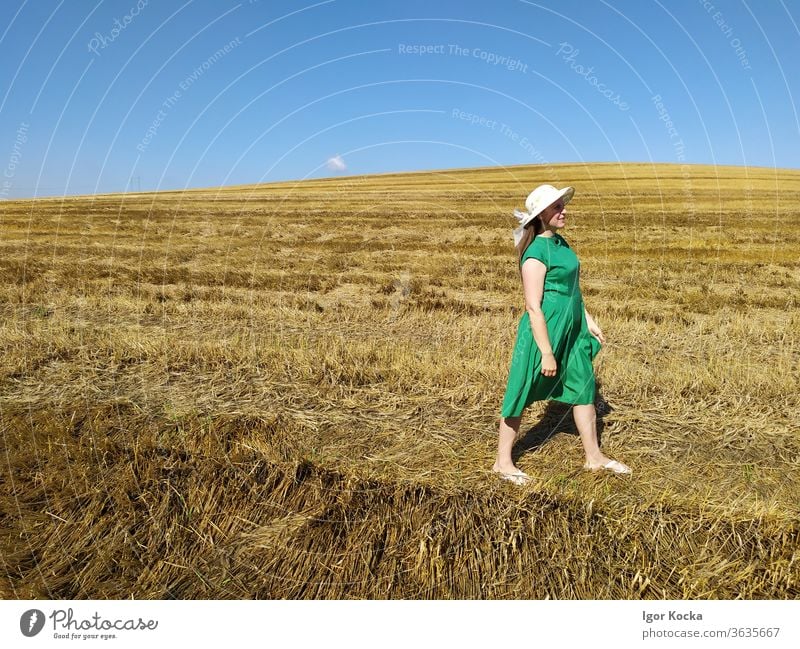 An Land gehende Frau laufen Feld Sommer Klarer Himmel grün Kleid Hut Wiese Landschaft Schönes Wetter Freiheit Lifestyle Textfreiraum