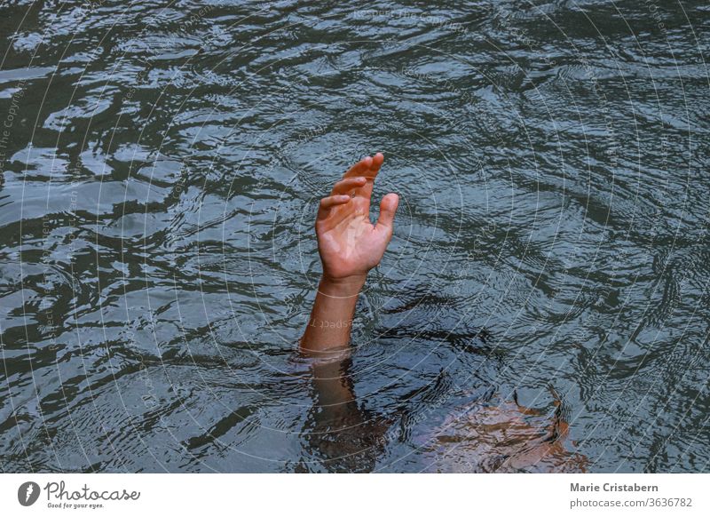 Eine Hand, die aus dem Wasser ragt, um das Konzept des Ertrinkens, der Krise der psychischen Gesundheit, der Depression und des Kampfes zu zeigen