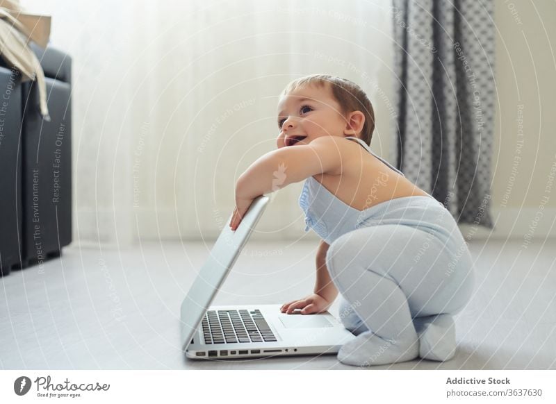 Fröhliches Baby spielt zu Hause mit dem Laptop Glück benutzend heimwärts spielen Kleinkind Apparatur modern Kindheit Lifestyle wenig allein heiter Gerät Netbook