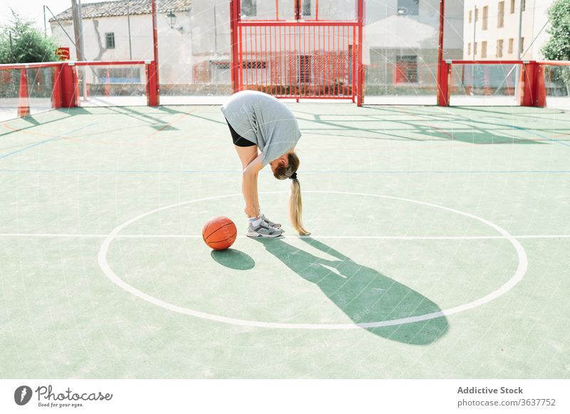 Basketballspieler beim Aufwärmen auf dem Sportplatz Frau Sportpark Übung Wegbiegung Training vorbereiten Spieler Ball Gericht Dehnung Aktivität Lifestyle