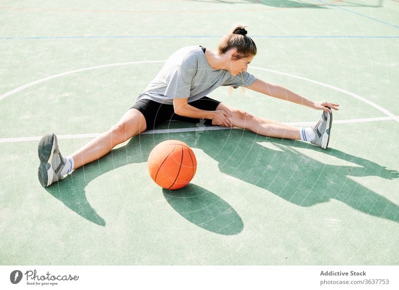 Basketballspielerin beim Stretching auf dem Sportplatz Frau Dehnung Übung Aufwärmen Sportpark Training vorbereiten Spieler Ball Gericht Aktivität Lifestyle