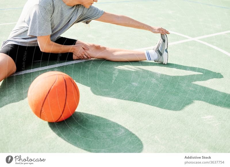 Basketballspielerin beim Stretching auf dem Sportplatz Frau Dehnung Übung Aufwärmen Sportpark Training vorbereiten Spieler Ball Gericht Aktivität Lifestyle