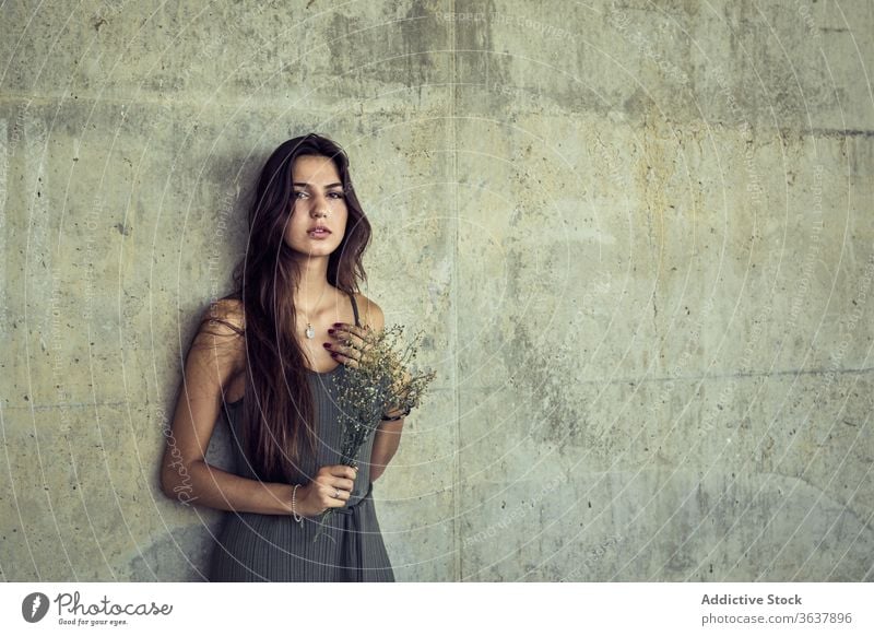 Sanfte Frau mit Wildblumen in der Stadt sanft Blume Blumenstrauß Großstadt Blütezeit frisch Gelassenheit Steinwand geblümt elegant Windstille Pflanze romantisch