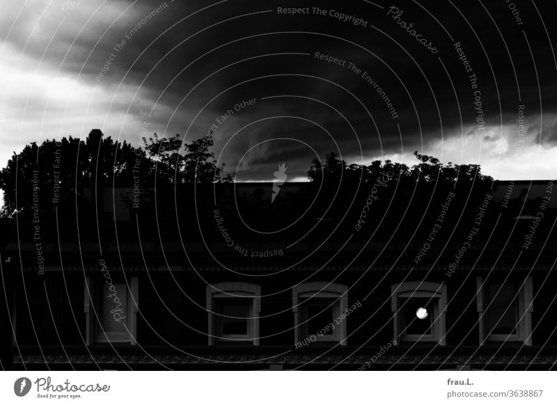 Der Tag verschwand in dunklen Wolken, doch gegenüber in der Dachgeschosswohnung leuchtet eine Lampe. Haus Architektur Fenster Altbau Himmel Abend Fassade
