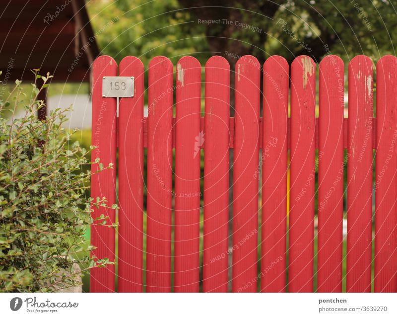 Ein rotes Gartentor in einer Schrebergartenanlage parzelle schrebergarten natur pflanzen spießig 153