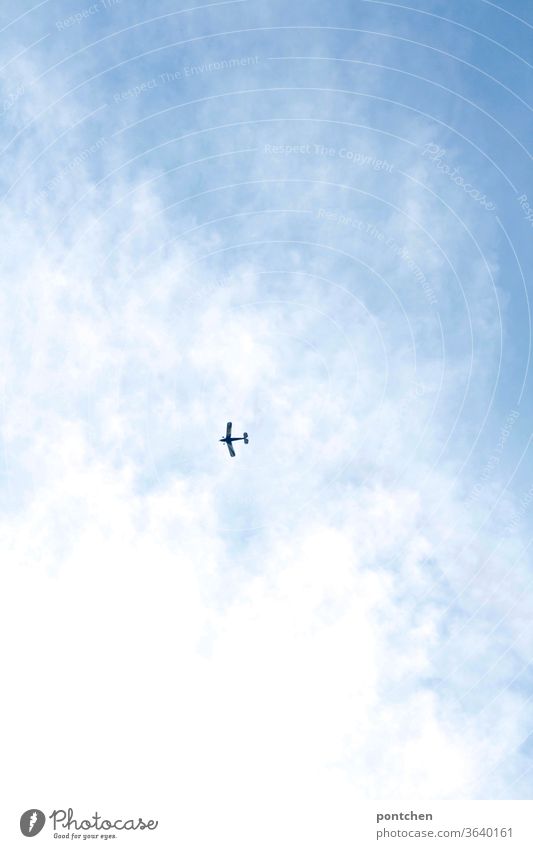 Froschperspektive- Ein kleines Flugzeug fliegt am blauen, bewölkten Himmel fliegen freiheit wolken himmel reisen fortbewegung Luftverkehr Tourismus Klimawandel