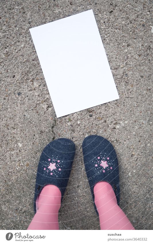 frau in hausschuhen steht vor einem auf der straße liegenden leeren weißen blatt papier, das beschriftet werden kann .. Frau stehen Hausschuhe Asphalt Straße