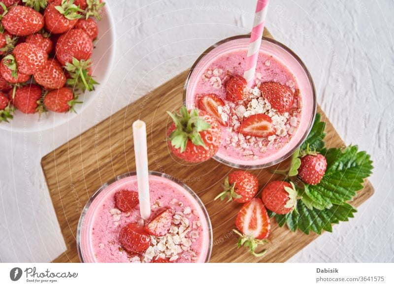 Erdbeermilchshake im Glas mit Stroh und frischen Beeren auf weißem Hintergrund Erdbeeren melken schütteln Saft Smoothie Cocktail Sahne Getränk gemischt