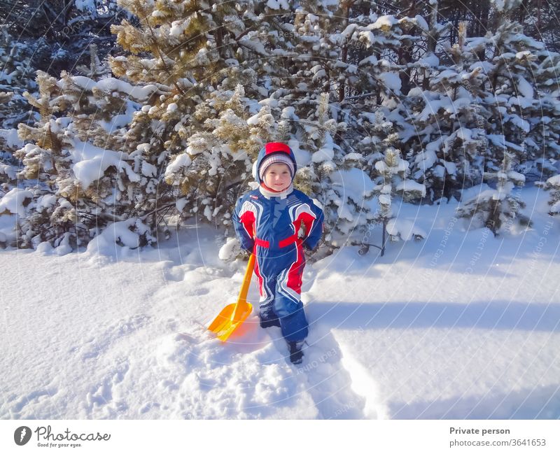 Glücklicher kleiner Junge im Winter in der Nähe eines verschneiten Weihnachtsbaums wenig Weihnachten Kind Spiele im Freien Kindheit Kleidung kalt niedlich