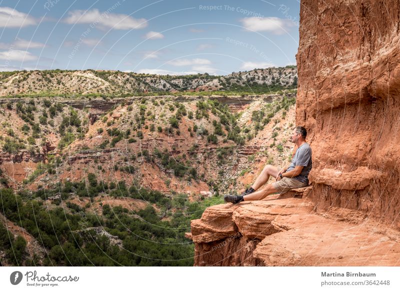 Am Rande des Lighthouse Rock sitzender Mann, Palo Duro Canyin State Park, Texas 50-54 wandern Wanderung aktiv Leuchtturm Felsen Schlucht wüst dramatisch Wolken