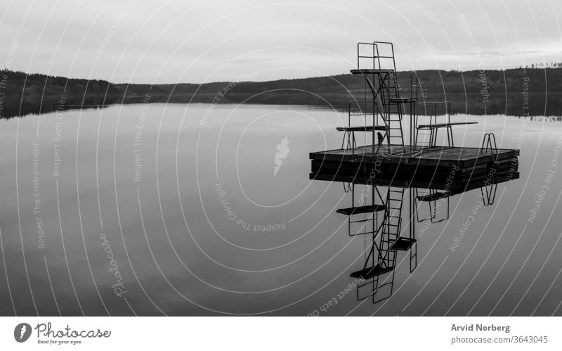 Schwarz-weißer Sprungturm mit 1, 2 und 3 Metern Höhe in einem ländlichen See in Schweden mit Spiegelung abstrakt erstaunlich Kunst Hintergrund Strand schön