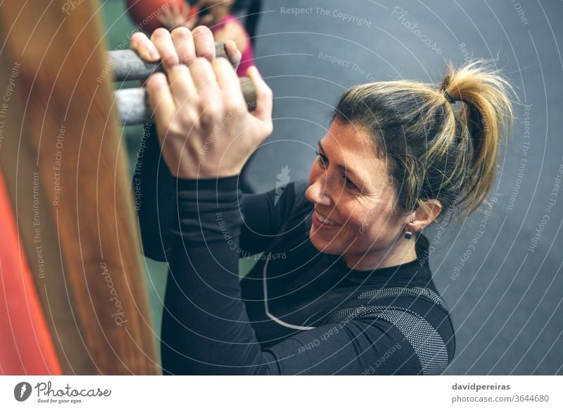 Frau, die an der Stecktafel hängt. Steckplatte aufhängen stark durchkreuzen passen Lächeln Training des Tages wod Übung Glück Fitness genießend Sport Sportlerin