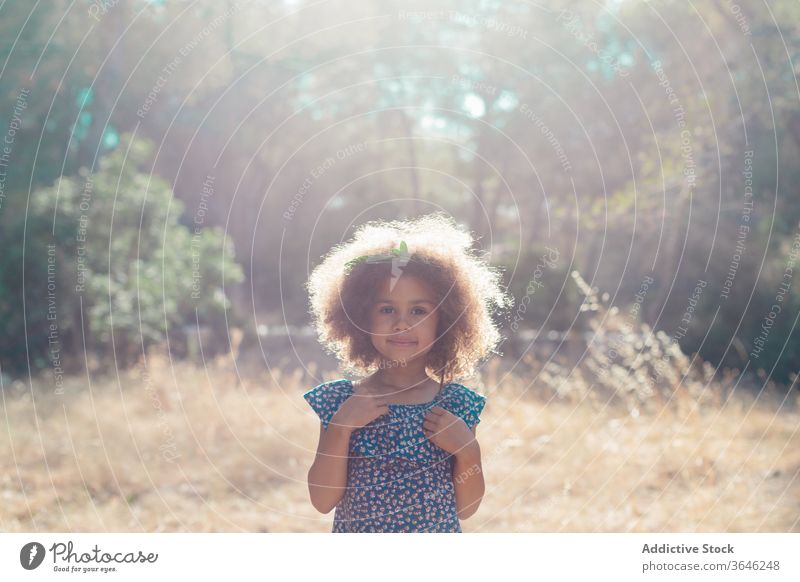 Ernstes kleines Mulattenmädchen auf verschwommenem Naturhintergrund Mädchen schwarz Kind ernst Porträt Windstille bezaubernd Sommer Stil Outfit emotionslos