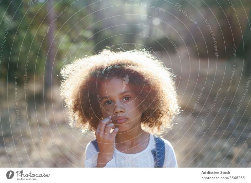 Ernstes kleines Mulattenmädchen auf verschwommenem Naturhintergrund Mädchen schwarz Kind ernst Porträt Windstille bezaubernd Sommer Stil Outfit emotionslos