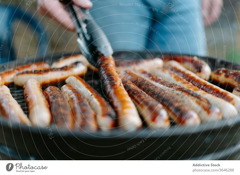 Erntehelfer beim Grillen von Würstchen auf der Grillpfanne Person Grillrost lecker Wurstwaren Barbecue Hinterhof geschmackvoll Koch tong Abendessen Sommer