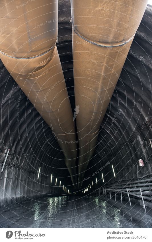 Unterirdisch beleuchteter Tunnel mit Pipeline Bergbau Stollen Durchgang Röhren Metall Licht leuchten unterirdisch Konstruktion Struktur Stein riesig breit