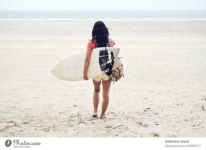 Anonyme Surferin, die mit einem Surfbrett am Strand spazieren geht Frau Spaziergang sandig führen Inhalt MEER lässig Seeküste sorgenfrei Aktivität jung