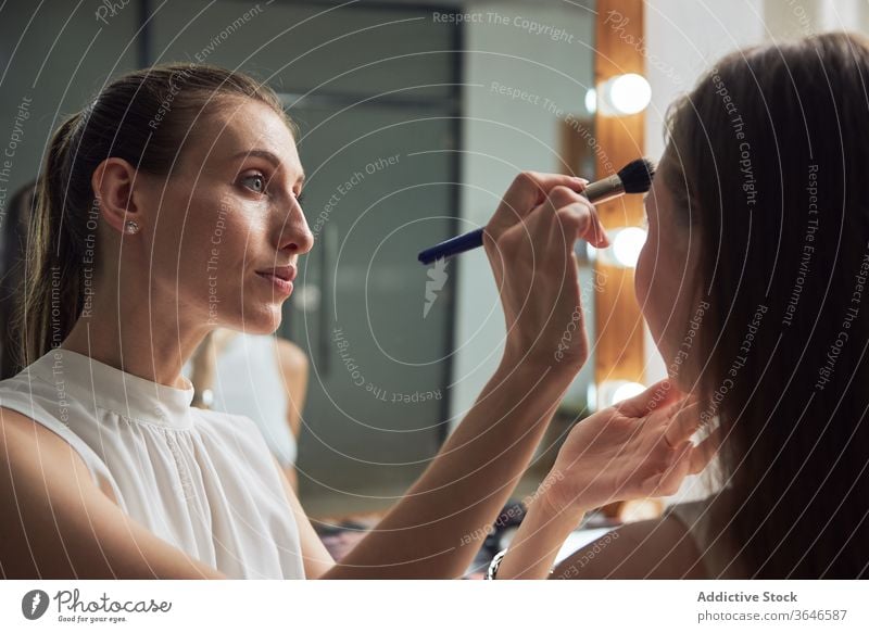 Professioneller Visagist trägt Puder auf das Gesicht des Modells auf visagiste Pulver Bürste Make-up Salon Spiegel Licht positiv bewerben Konzentration Kosmetik