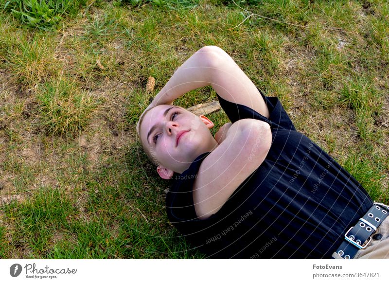 Mädchen mit sehr kurzem Haar liegt im Gras, Arme im Nacken und Kopf Porträt krank Natur Medizin Mode jung Schönheit Krebs Boden Frau attraktiv Therapie wirklich