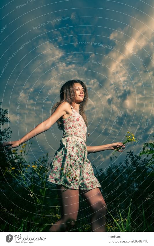 Glückliches Mädchen rennt in der Nacht mit gelben Wildblumen in der linken Hand über die Sommerfelder Beine Tanzen Teil von Körper Kleid springen aktiv Frau