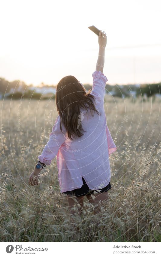 Zufriedene Frau bei Sonnenuntergang auf dem Land Feld Selfie Landschaft Smartphone benutzend malerisch ländlich Foto getrocknet Gerät Apparatur Natur Wiese