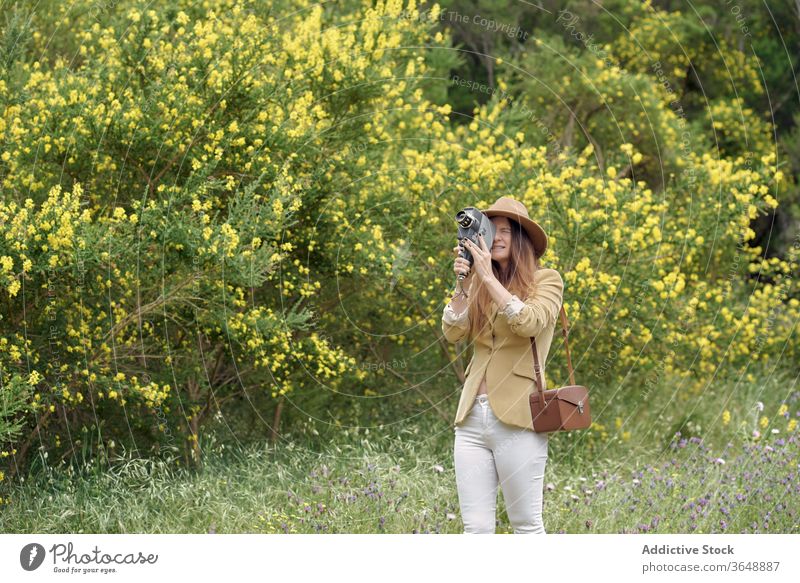 Fotograf, der mit einer alten Videokamera im Garten Videoaufnahmen macht Aufzeichnen Fotokamera Augen geschlossen Blütezeit Blume Baum Park Ast fokussiert