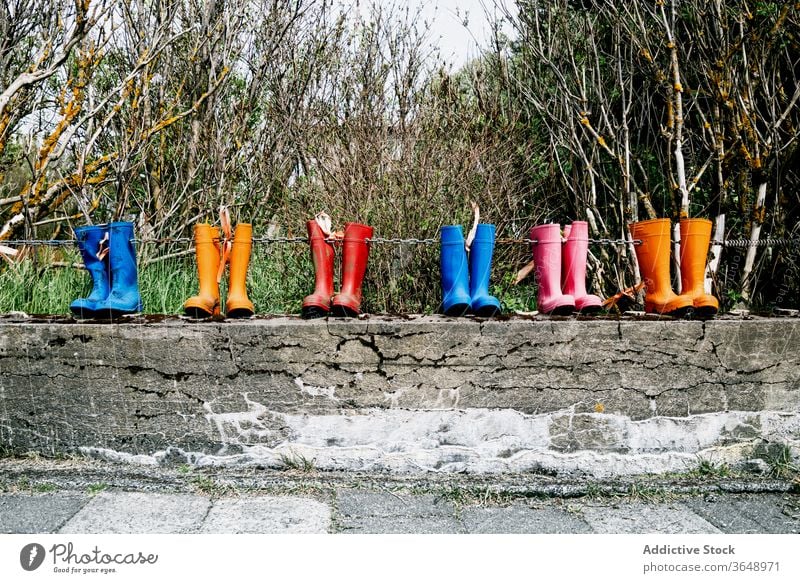 Gummistiefel auf Metallkette Stiefel Schuhe Zaun Landschaft Paar kreativ farbenfroh pulsierend Borte Stein anketten hell rustikal ländlich verwittert schäbig