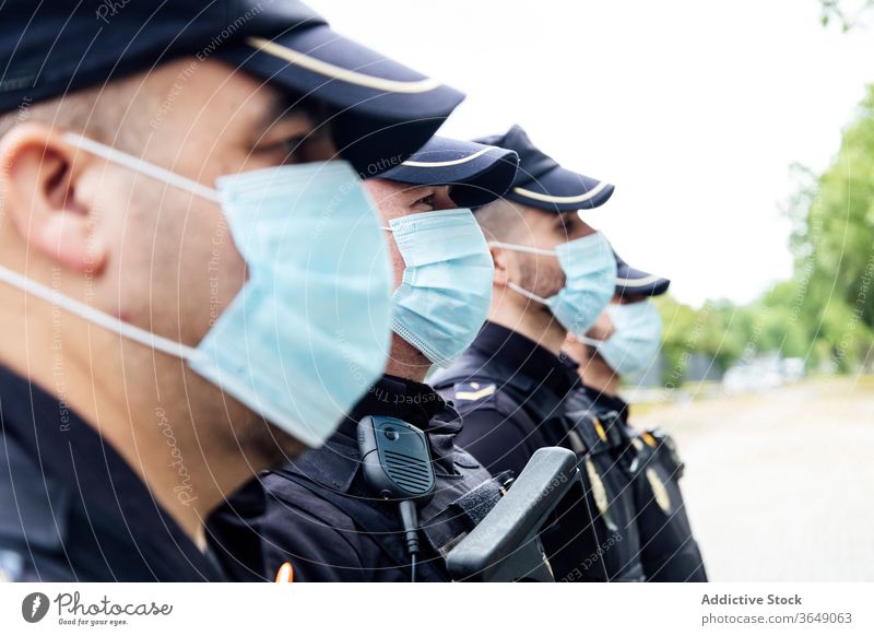 Polizisten mit medizinischen Masken stehen auf der Straße gegen Dienstwagen Männer Patrouille Polizei behüten Kontrolle ernst Sicherheit Arbeit professionell