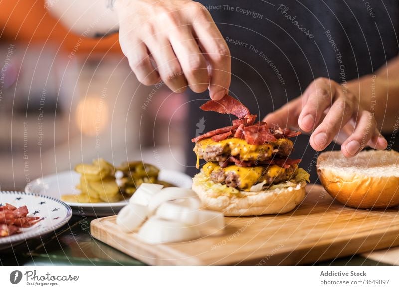 Asiatischer Koch bereitet Burger im Cafe zu geschmackvoll vorbereiten Mann Fleisch Kotelett hinzufügen Lebensmittel Café asiatisch ethnisch lecker Mahlzeit