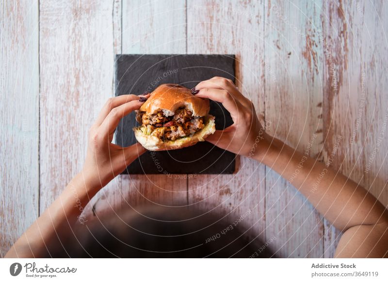 Erntehelferin mit Burger im Cafe lecker Café Frau essen genießen geschmackvoll Schiefer Holzplatte Hamburger Tisch hungrig Mittagessen Lebensmittel Mahlzeit