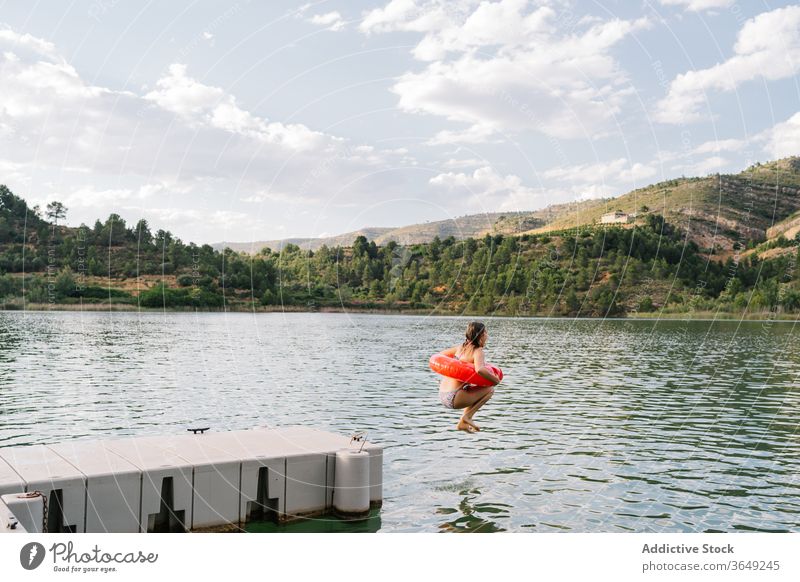 Mädchen springt mit aufblasbarem Ring in den See springen Gummi Teich Bikini Sommer Urlaub Spaß haben Teenager Moment Wasser Glück Erholung sich[Akk] entspannen